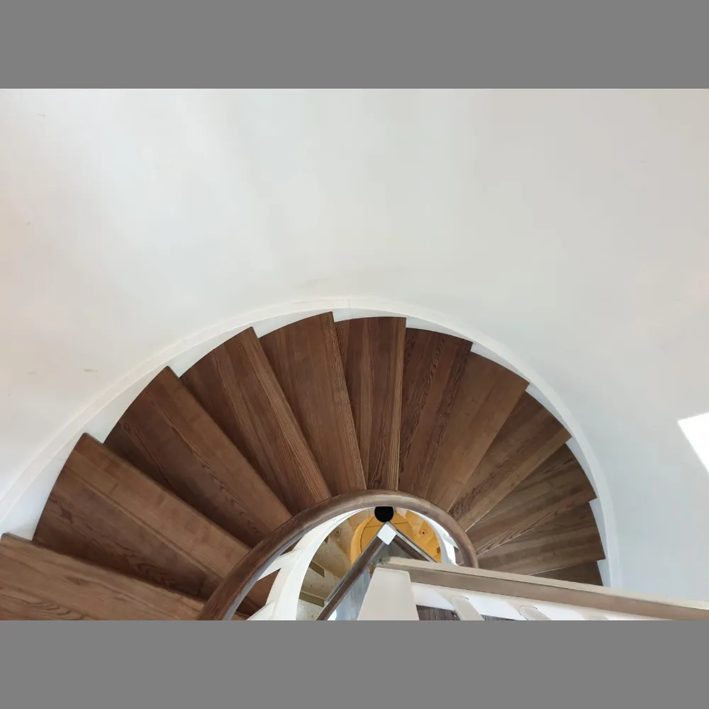 Blick von oben in eine gewendelte Holztreppe